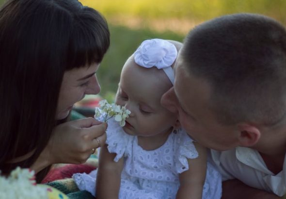 A loving family moment with parents and baby at a sunny outdoor picnic.